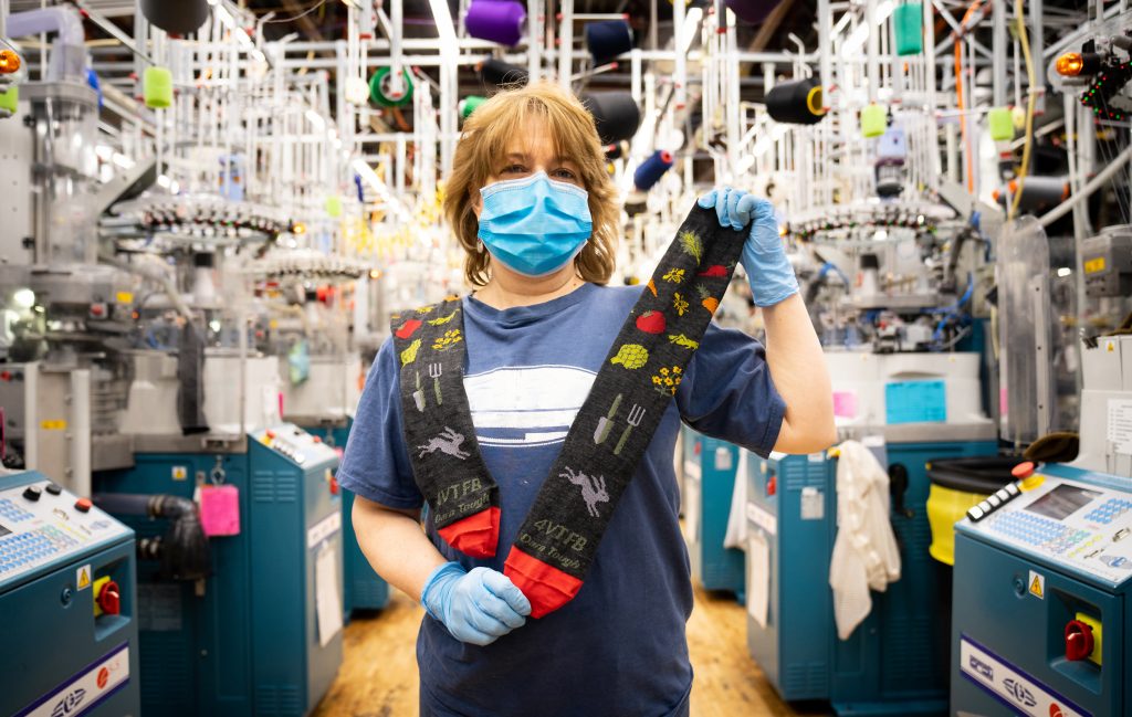 Person wearing mask holding patterned socks.