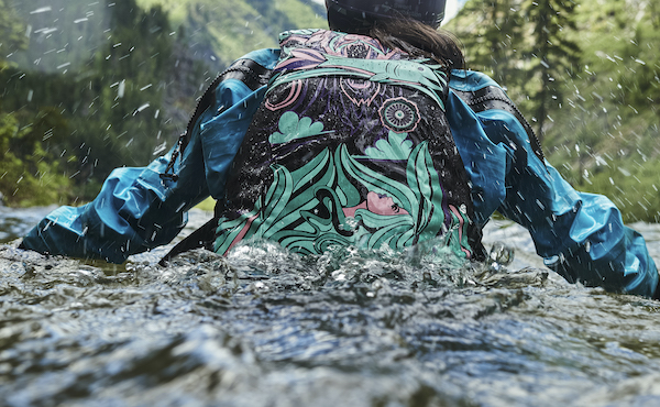 A photo of a woman standing in torso-high water displaying the Layla Limited Edition PFD.